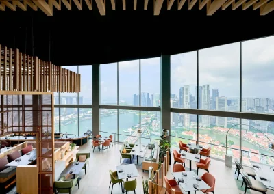 The interior of SKAI restaurant featuring modern décor and large windows overlooking Singapore